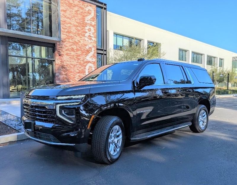 Black Chevrolet Suburban luxury SUV in front of modern building