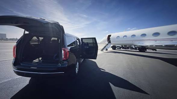 Black luxury SUV with open door next to private jet on tarmac